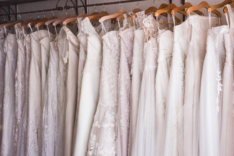 wedding dresses hanging up in a line 