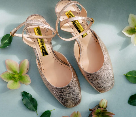 gold heeled shoes on blue background with flowers