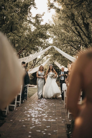 mother of the bride and daughter walking down the aisle 