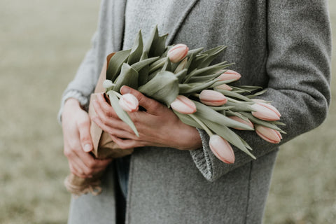 woman wearing grey jacket holding pink flowers