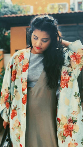 woman standing wearing brown dress and rose statement jacket 