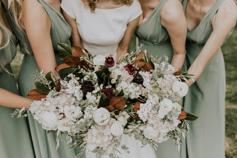 bride and bridesmaids in light green dresses holding flowers