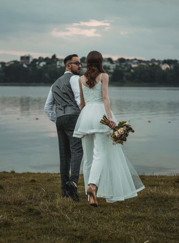 bride and groom walking towards water