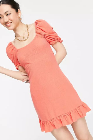 a woman is pictured smiling whilst wearing a coral ASOS dress.