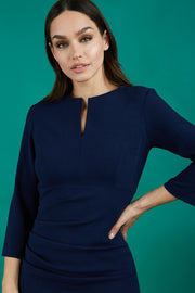 model is wearing diva catwalk chandos sheath dress with three quarter sleeve and slit in the middle of the neckline in navy blue front