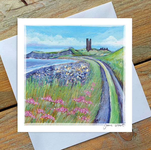 A greetings card featuring the ruins of Dunstanburgh Castle with a sprinkling of sea thrift beside the coastal path leading to the ancient ruin. 