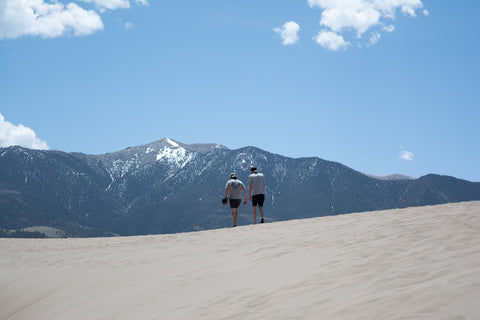 Two people walking on the sand dunes