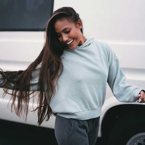 woman wearing a green hoodie standing in front of a white van
