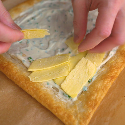 Adding shaved vegan cheese to puff pastry tart