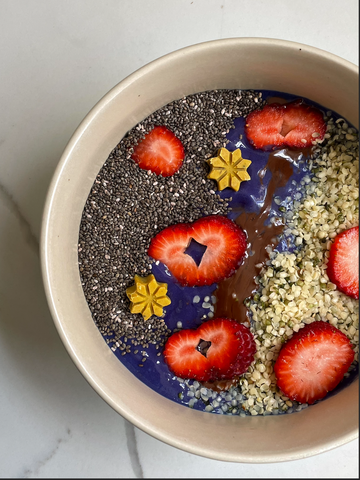 Blue Smoothie Bowl topped with chia seeds, hemp seed and bright red strawberries