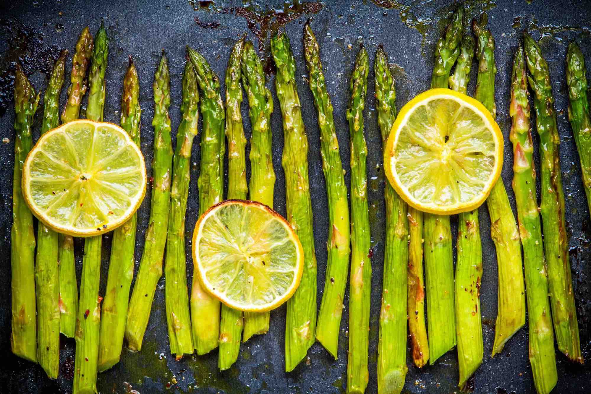 Row of roasted asparagus with lemon slices layed on top