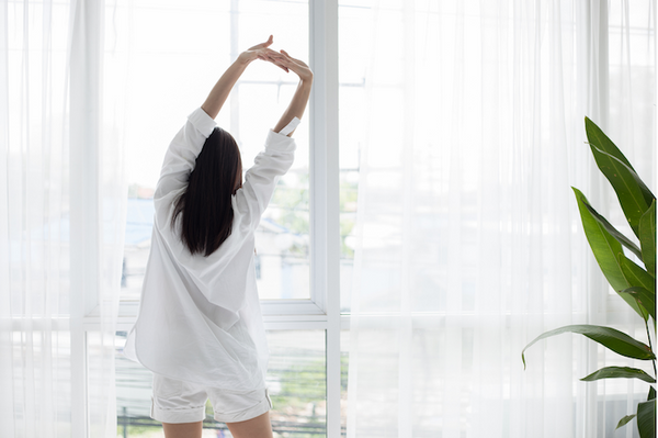 woman stretching in the morning sunlight after waking up