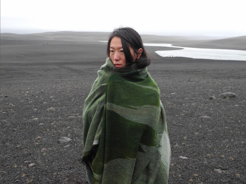 A girl wrapped in a handmade wool blanket in the middle of the desert