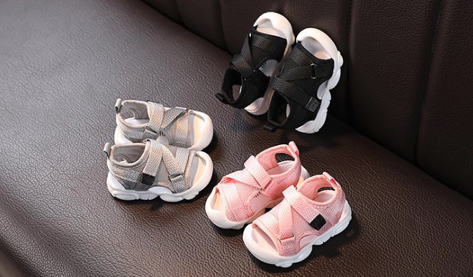 Tres pares de sandalias de bebe sobre sofa de cuero