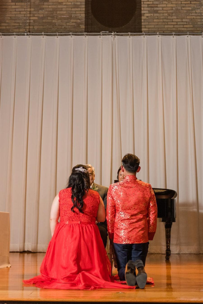 Couple in Chinese wedding tea ceremony outfits kneeling 