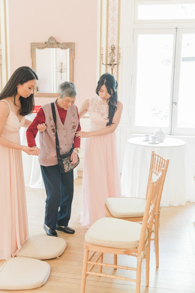 Wedding tea ceremony attendants bridesmaids helping elder to chair