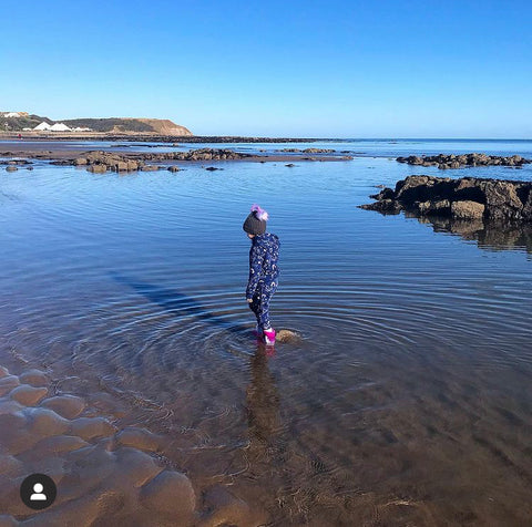 Evie with bobble hat and wellies paddling in North Bay, Scarborough