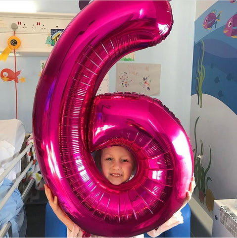 Evie holding pink number 6 balloon, Leeds General Infirmary
