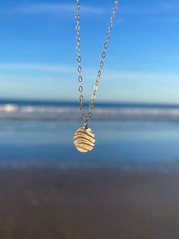 Small 9ct Gold Ripple Pendant on chain with sea in the background by Kate Wimbush Jewellery