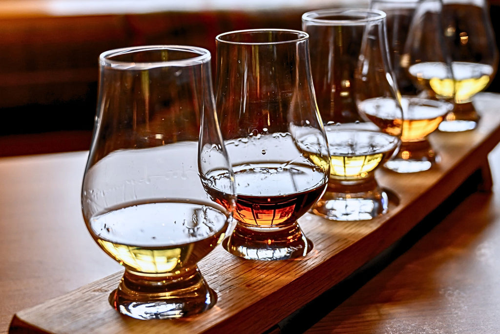 a row of whisky glasses with different coloured whiskies in them