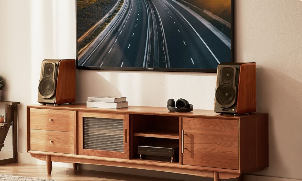 Edifier S1000MKII Bookshelf Speakers On Sideboard Underneath a TV with headphones next to them