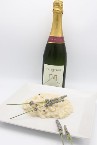 Bottiglia di Blanquette de Limoux Tradition della cantina Antech dietro al piatto di risotto alla Lavanda polesana. 