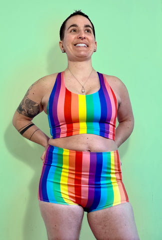 Queer person wearing a rainbow binder and rainbow shorts