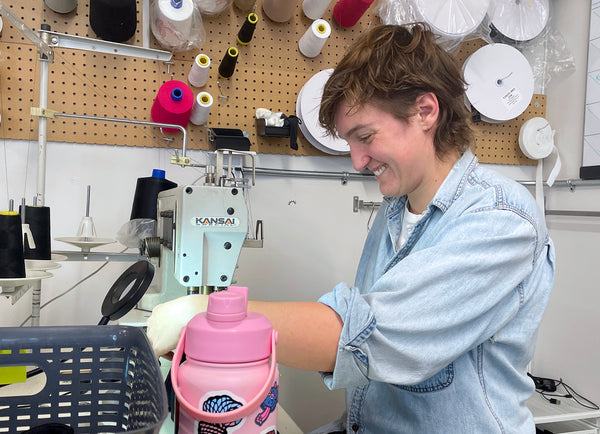 An Origami Customs employee at a sewing machine sewing custom clothing in the clothing studio
