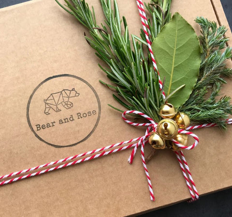 Gift in brown box with bakers twine bells and foliage sprig
