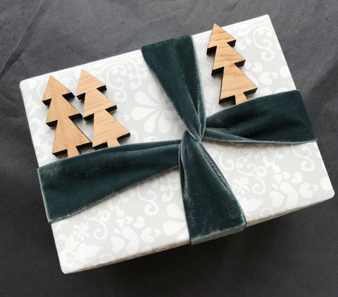Gift wrapped present with small wooden trees tucked in velvet ribbon
