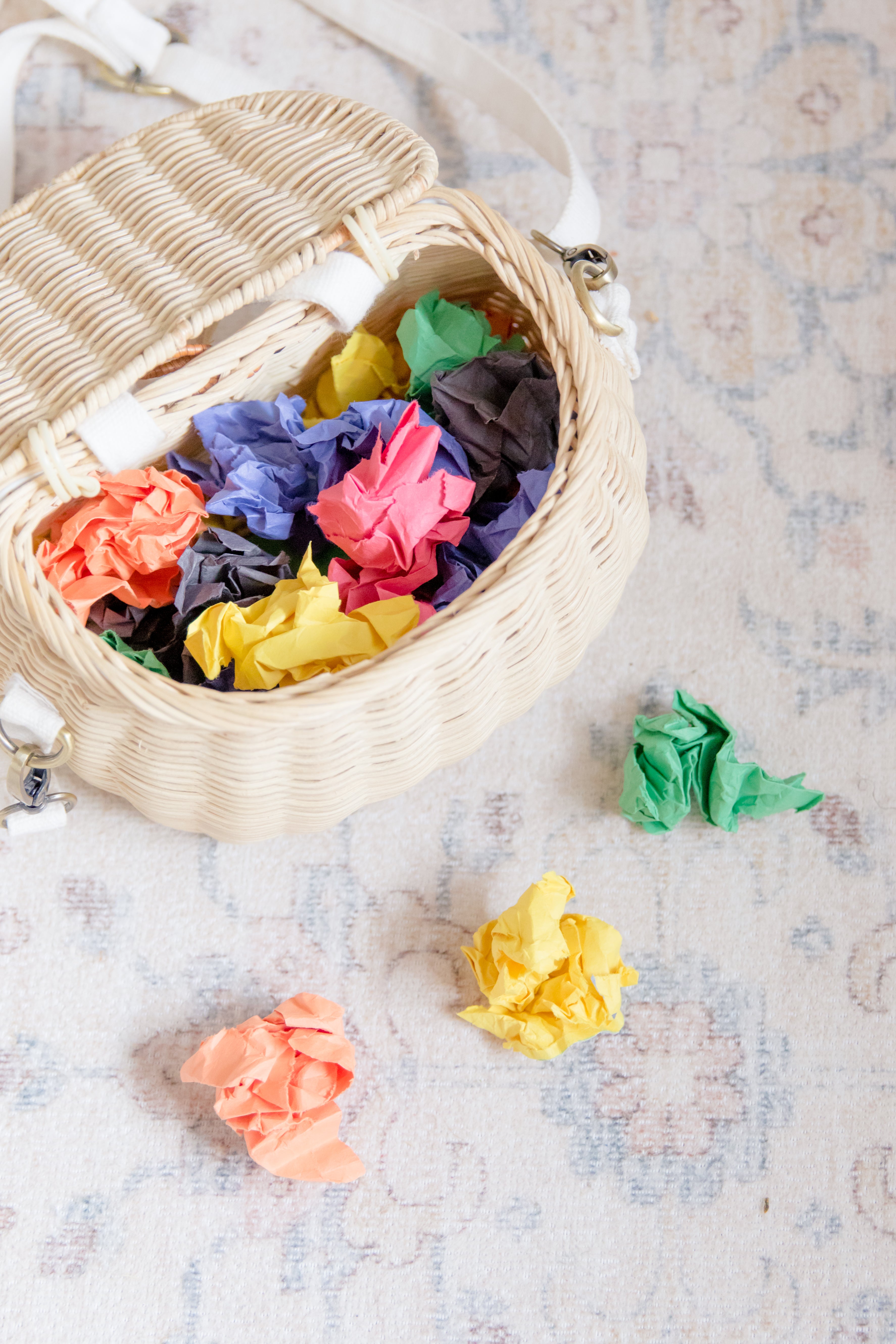 A wicker basket filled with crumpled pieces of multi-colored paper