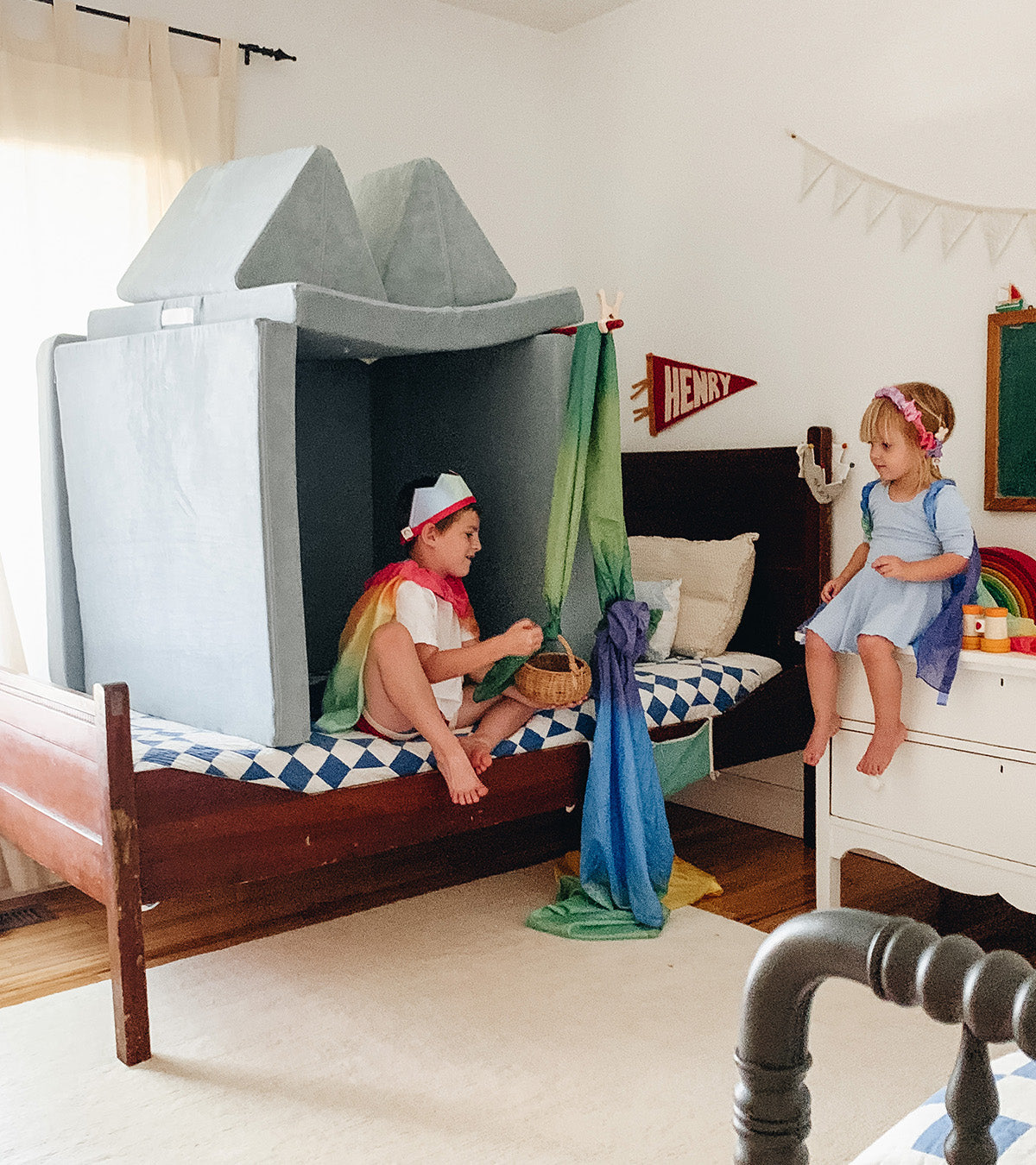 Two children sit on top of their bed under a Surfside Nugget set up like a house