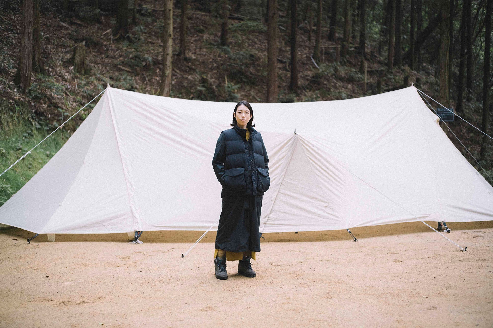woman in black stands in front of snow peak tent