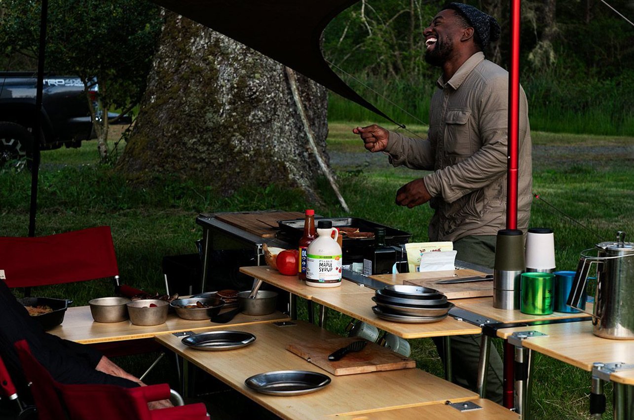 a man cooking with snow peak IGT system kitchen in a garden