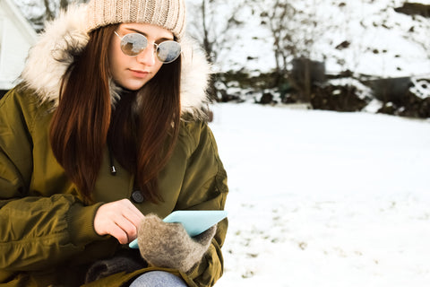 A girl in a winter park looks at the screen of a tablet, smartphone - InterPlexus Blog Immune Support