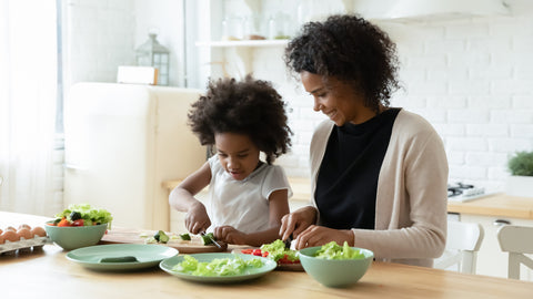 Happy biracial mom and little daughter cook together