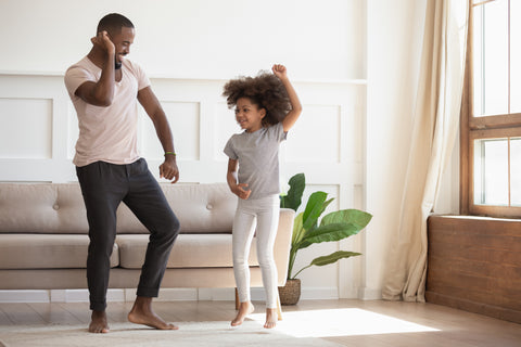 In living room african father dancing with little daughter