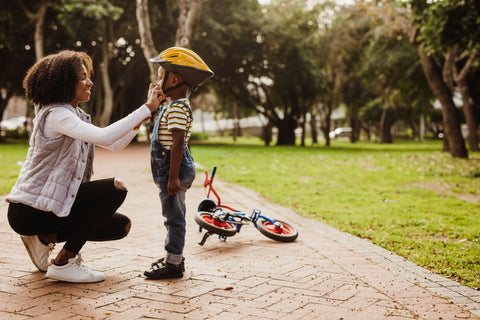 Optimal Fertility - Mother Helping Healthy Son with Bike Helmet 