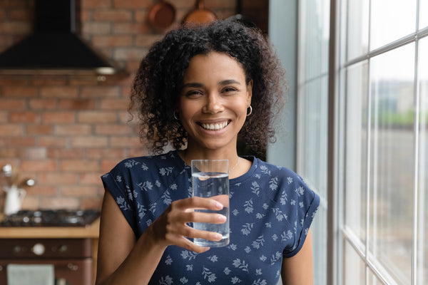 Happy young multiracial ethnic woman holding glass of water