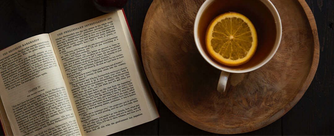 A hardcover book placed on a wooden table, ready to be read.