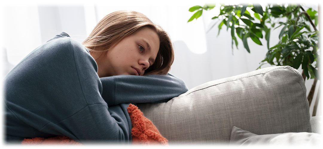 Concerned young adult resting on a couch, showcasing the need for Lily & Loaf's stress-relief products.