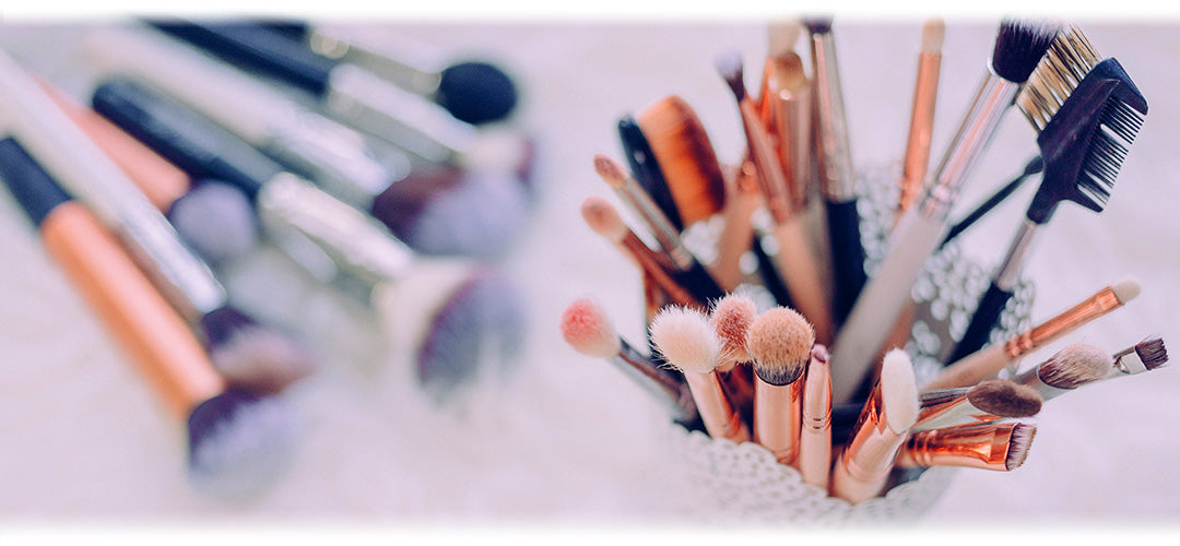 An image featuring an assortment of makeup products including lipsticks, eyeshadow palettes, brushes, and compacts, arranged artistically on a white background. The image represents a selection of makeup essentials for creating diverse beauty looks.