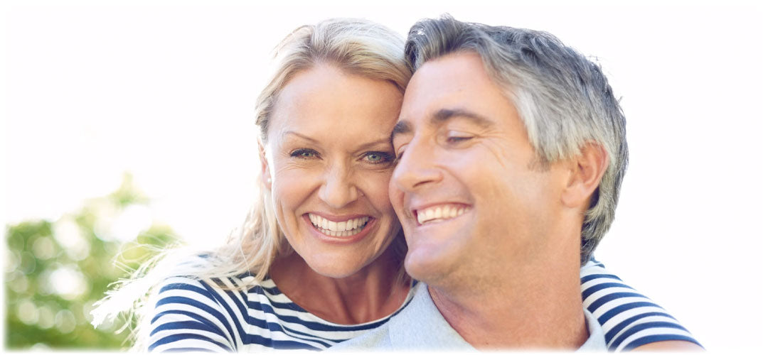 Smiling mature couple in striped shirts, embracing each other outdoors. They radiate happiness and a strong, loving bond.