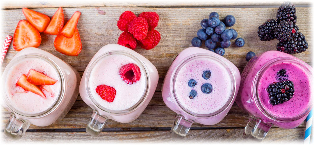 an image of two red berry smoothies, one topped with strawberries, the other raspberries