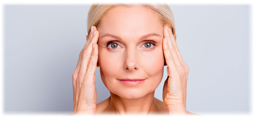 A woman with radiant, youthful-looking skin is gently touching her temples, reflecting the potential skin health benefits