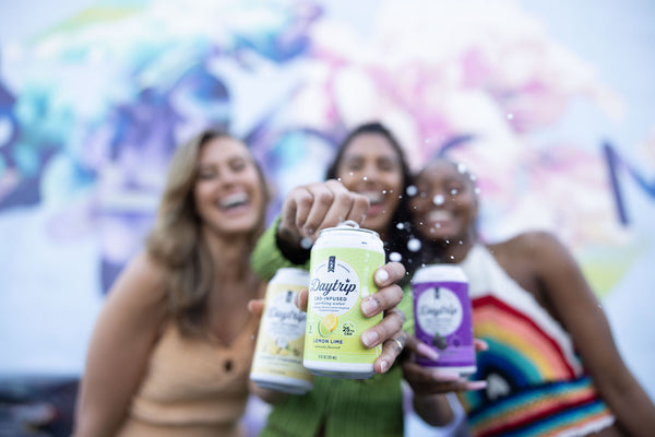 three ladies cracking open an ice cold can of daytrip