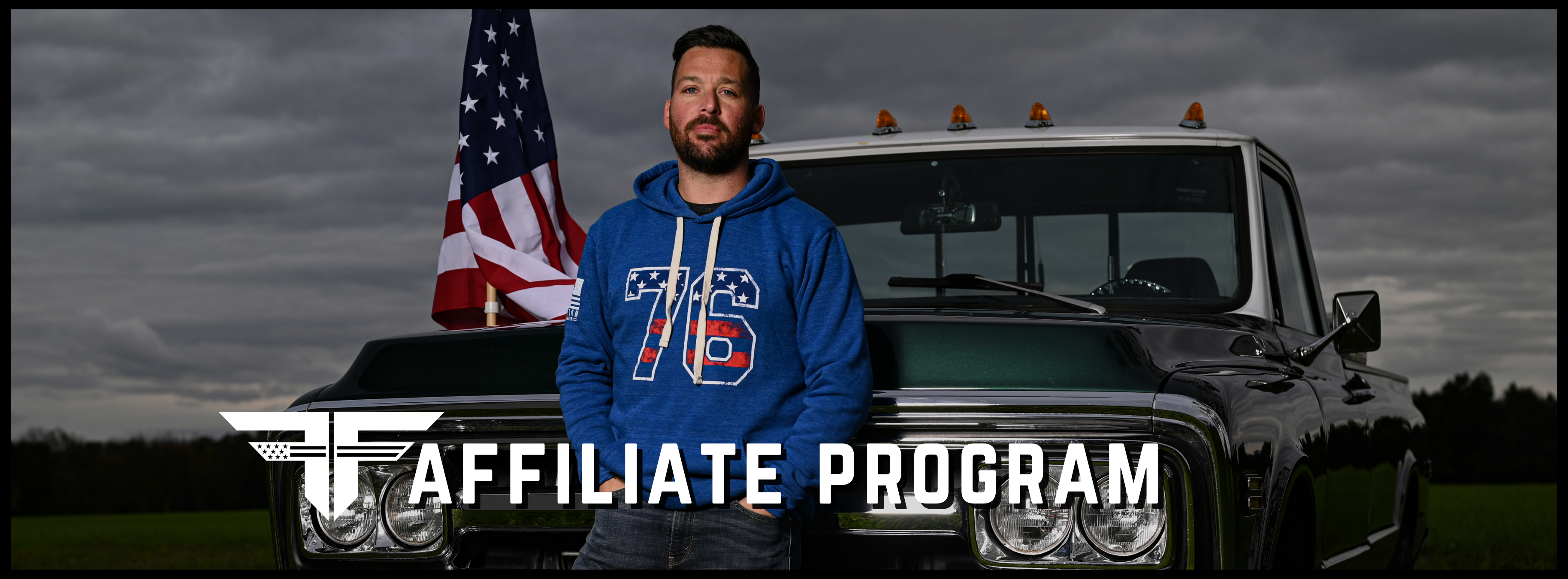 Man in a patriotic hoodie with a classic truck and flag