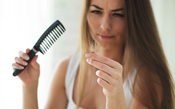 woman losing hair holding brush