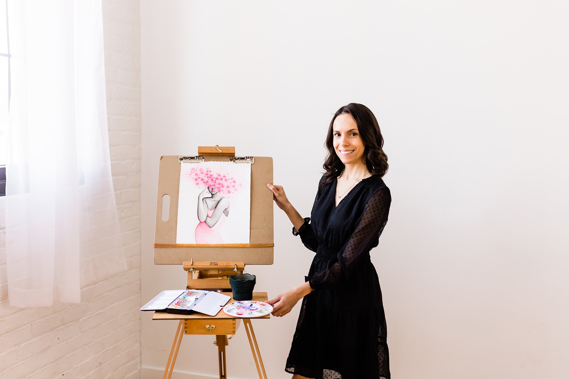 Watercolor artist Maria Ahrens posing with painting on easel