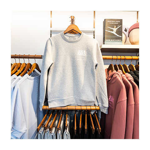 Grey Royal Ballet sweatshirt hanging on a rack with other ballet clothes.